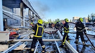Firefighters work to extinguish a fire at a shopping center burned after a rocket attack in Kremenchuk on 27 June 2922