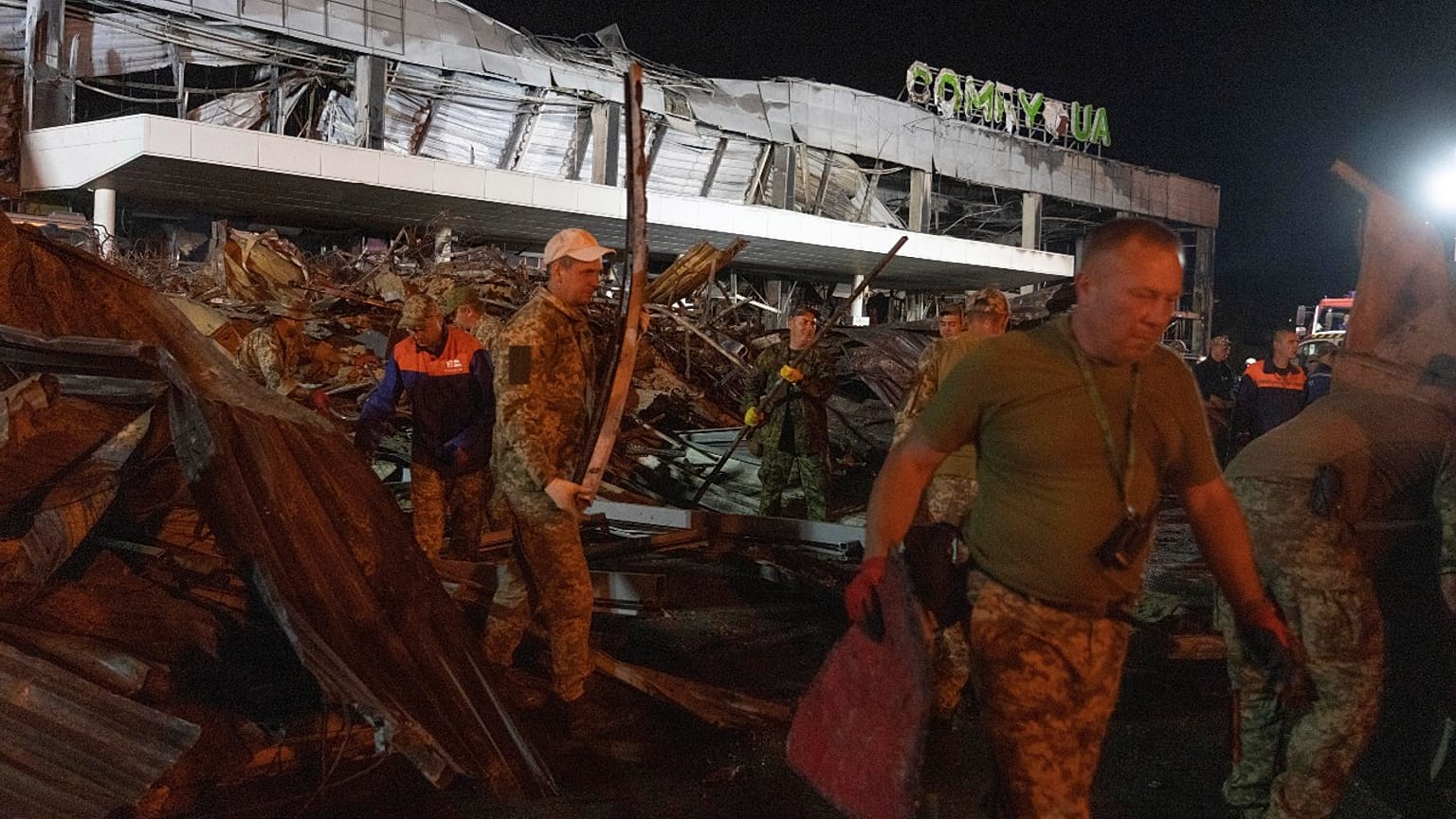 Volunteers work to take away debris at a shopping center burned after a rocket attack in Kremenchuk, Ukraine, early Tuesday, June 28, 2022. 