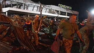 Volunteers work to take away debris at a shopping center burned after a rocket attack in Kremenchuk, Ukraine, early Tuesday, June 28, 2022. 