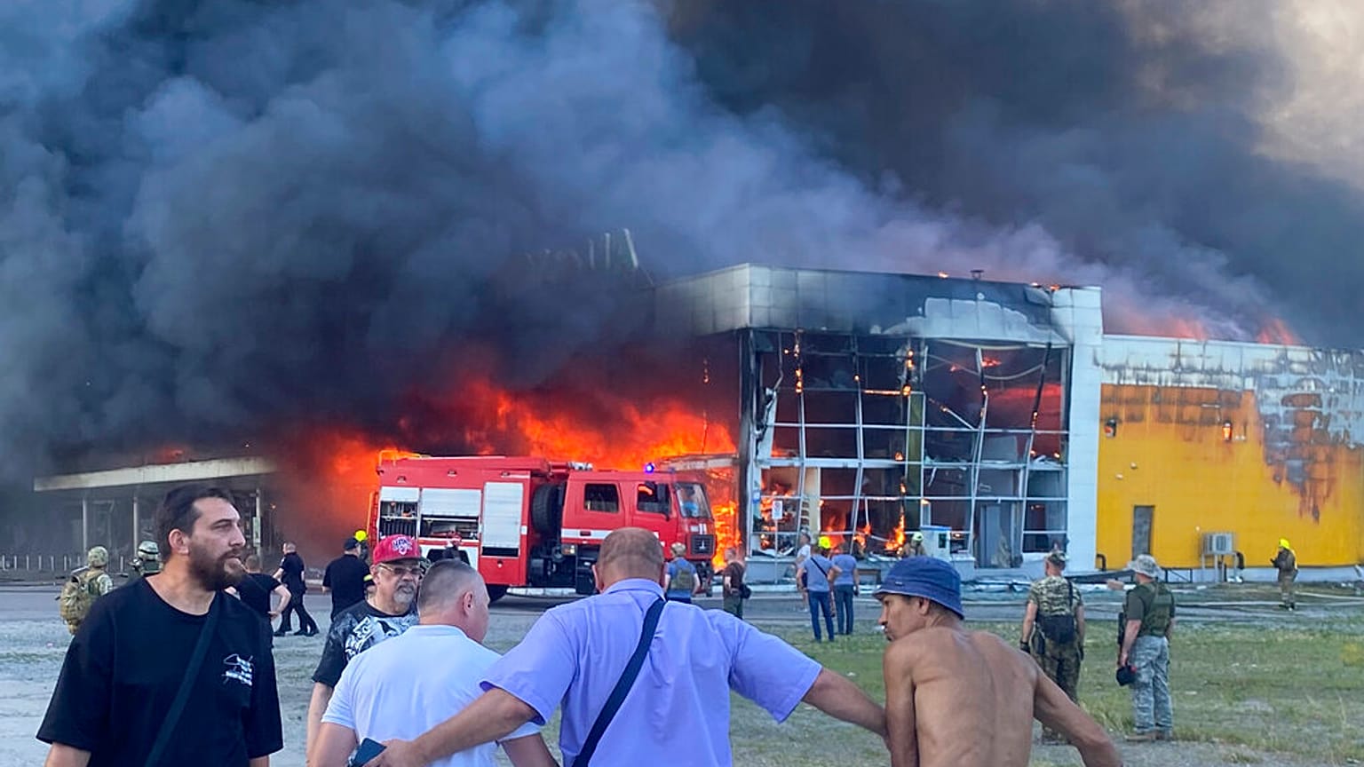 Πολίτες παρακολουθούν από απόσταση την πυρκαγιά και τους καπνούς από το εμπορικό κέντρο που δέχτηκε πυραυλικό χτύπημα στο Κρεμεντσούκ