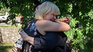 People react at a shopping center burned after a rocket attack in which dozens of people are feared killed and injured, Kremenchuk, Ukraine, Tuesday, June 28, 2022.