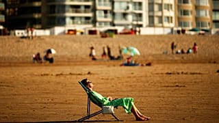 Egy nő napozik a belgiumi Knokke-Heist strandján 2020 július 31-én