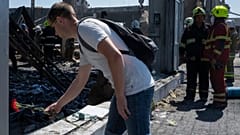 Ein Mann legt an der Ruine des Einkaufszentrums eine Blume nieder