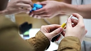 صورة أرشيفية لزوّار يجربون جهازاً لتدخين التبغ المسخّن في متجر "أي كيو كيو إس" بالعاصمة اليابانية، طوكيو، 22 أكتوبر 2018.