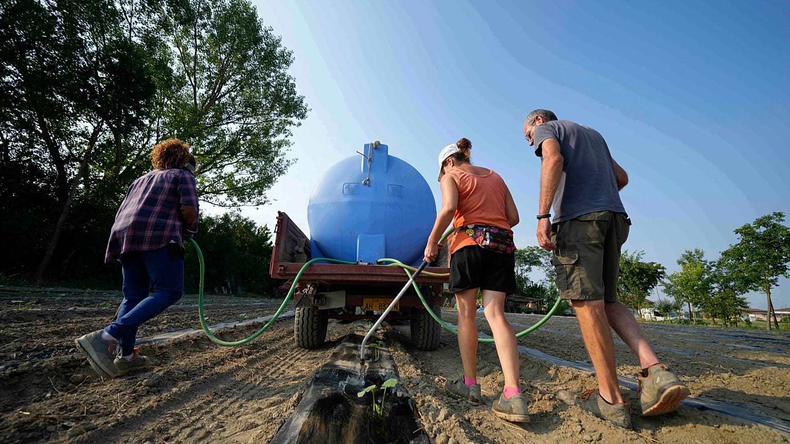 Gli agricoltori irrigano un campo di zucche utilizzando una pompa di sollevamento dell'acqua vicino al fiume Po a Guastalla, Italia, mercoledì 15 giugno 2022.