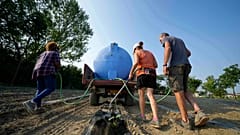 Gli agricoltori irrigano un campo di zucche utilizzando una pompa di sollevamento dell'acqua vicino al fiume Po a Guastalla, Italia, mercoledì 15 giugno 2022.