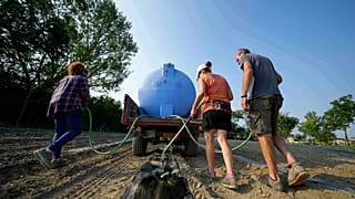Gli agricoltori irrigano un campo di zucche utilizzando una pompa di sollevamento dell'acqua vicino al fiume Po a Guastalla, Italia, mercoledì 15 giugno 2022.