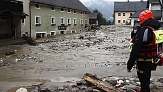 Rescue workers stand among damaged houses after heavy rain in Treffen.