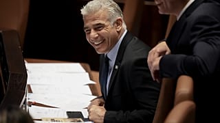Israeli Foreign Minister Yair Lapid smiles ahead of the vote on a bill to dissolve parliament, at the Knesset, Israel's parliament, in Jerusalem, Thursday, June 30, 2022.