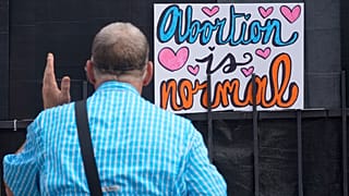 Un activista antiaborto frente a un cartel que dice que "El aborto es normal" fuera de la clínica de la Organización de Salud de la Mujer de Jackson, Mississippi, 30/6/2022