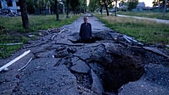 Viktor Shevchenko permanece en un cráter para mostrar su profundidad creada por un proyectil tras un ataque ruso en el distrito de Saltivka en Járkov, Ucrania. 01/07/2022