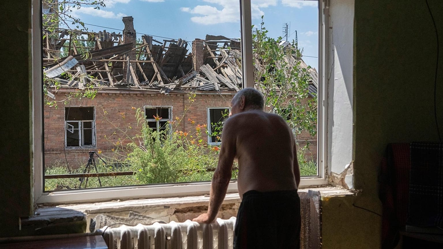 Victor Rosenberg, 81, looks out of a broken window in his home destroyed by the Russian rocket attack in the city centre of Bakhmut, Donetsk region, Ukraine, Friday, July 1, 2