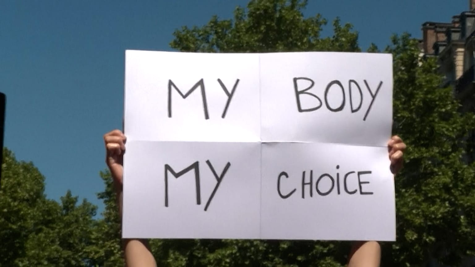 Demonstrators holding up signs and chanting slogans while marching