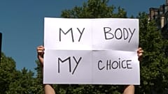 Demonstrators holding up signs and chanting slogans while marching