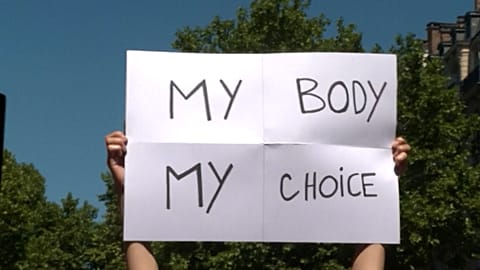 Demonstrators holding up signs and chanting slogans while marching