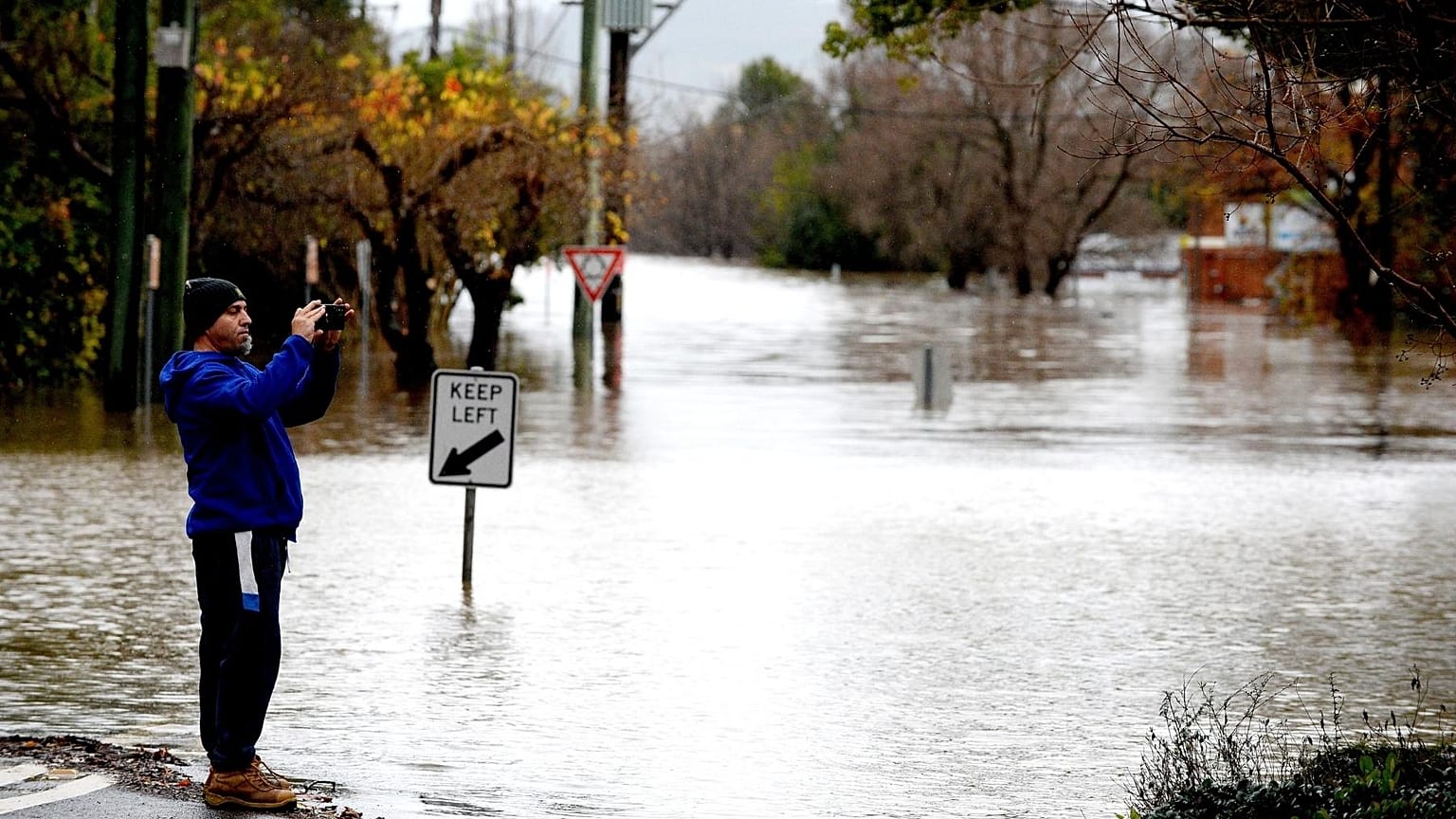 A man takes pictures of the flooded streets due to torrential rain in the Camden suburb of Sydney on July 3, 2022. 