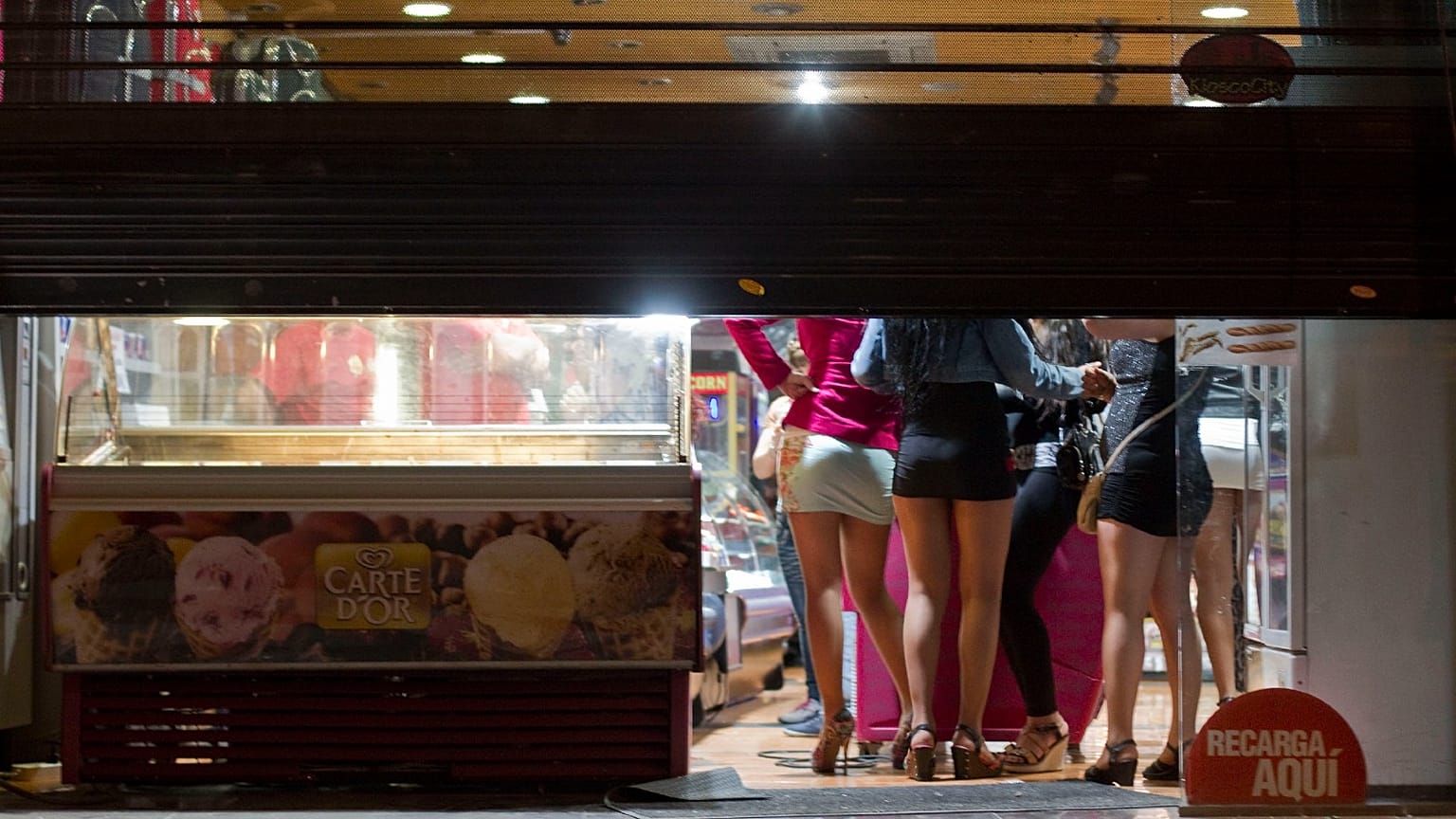 Prostitutes hide from riot police inside of a store during the eviction of a few activists who gathered at Puerta del Sol square in Madrid, Spain, in 2012