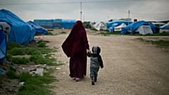 En esta foto de archivo de 2019, Samira, una ciudadana belga casada con un miembro francés del Estado Islámico, Karam El-Harchaoui, camina con su hijo en el campamento Roj