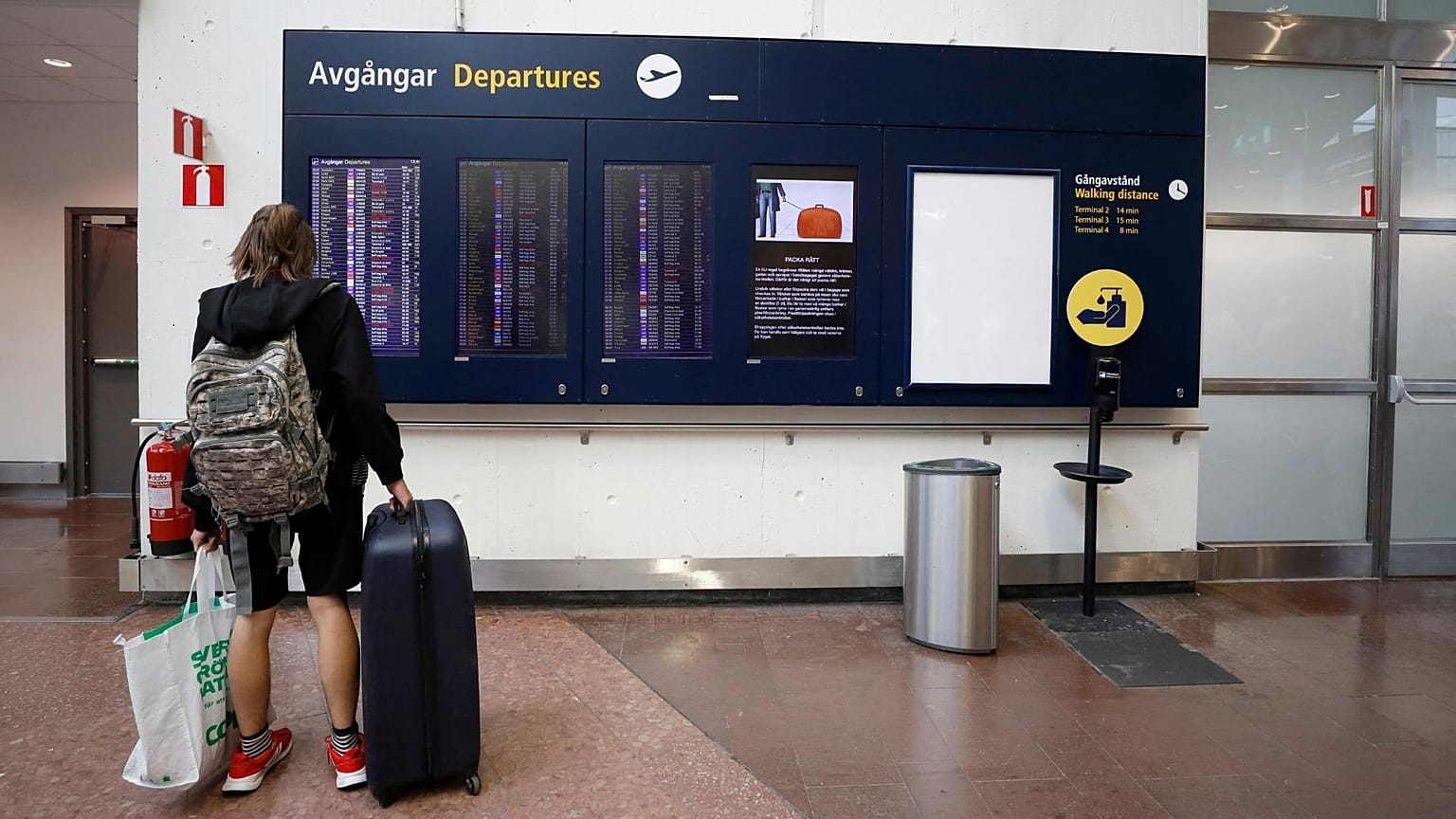 A passenger looks at the flight information board in the departure hall at Arlanda airport, Stockholm, Sweden.
