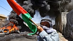 رجل فلسطيني مسن يحمل العلم الوطني في أعقاب مظاهرة ضد مصادرة إسرائيل للأراضي الفلسطينية في قرية كفر قدوم. 2022/07/01