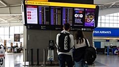 A couple looks at an electronic flight information board at Terminal 5 of London’s Heathrow Airport.