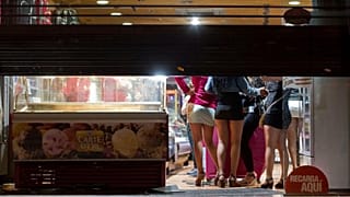 Prostitutes hide from riot police inside of a store during the eviction of a few activists who gathered at Puerta del Sol square in Madrid