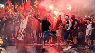 People light flares and throw eggs and stones on the foreign ministry building during a protest in Skopje, North Macedonia, late Tuesday, July 5, 2022.