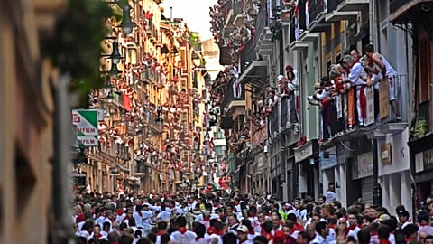 La gente corre por las calles delante de los toros de lidia durante el primer día de los encierros de las fiestas de San Fermín en Pamplona, el jueves 7 de julio de 2022