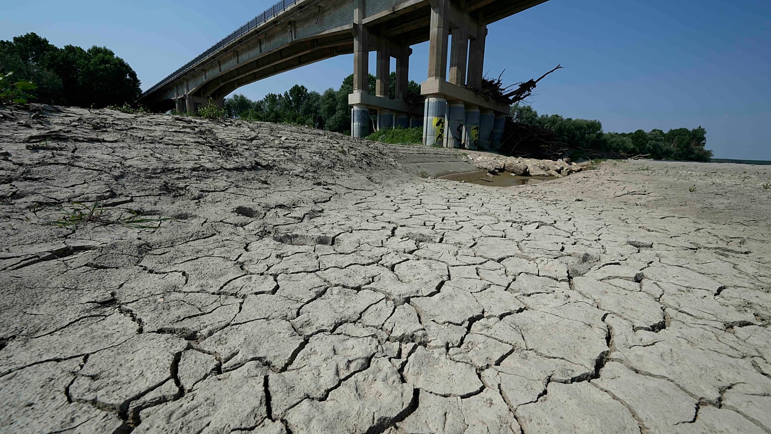 Dry cracked land is visible under a bridge in Boretto on the bed of the Po river, Italy, Wednesday, June 15, 2022