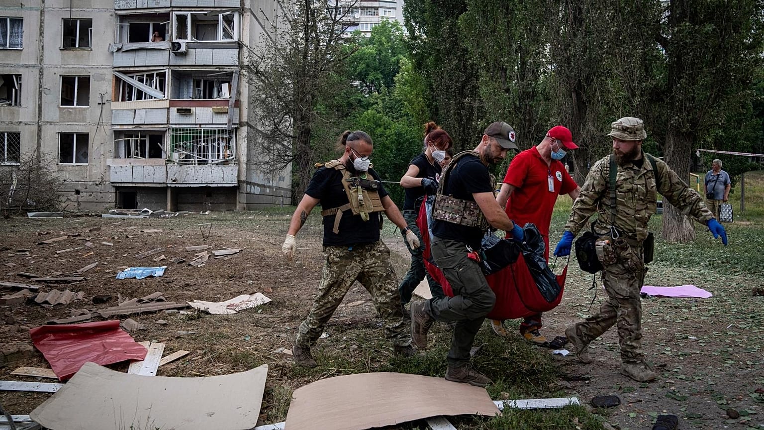 Paramedics carry the body of a woman who was killed during a Russian bombardment at a residential neighborhood in Kharkiv, Ukraine, on Thursday, July 7, 2022.