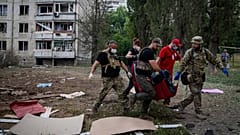 Paramedics carry the body of a woman who was killed during a Russian bombardment at a residential neighborhood in Kharkiv, Ukraine, on Thursday, July 7, 2022.