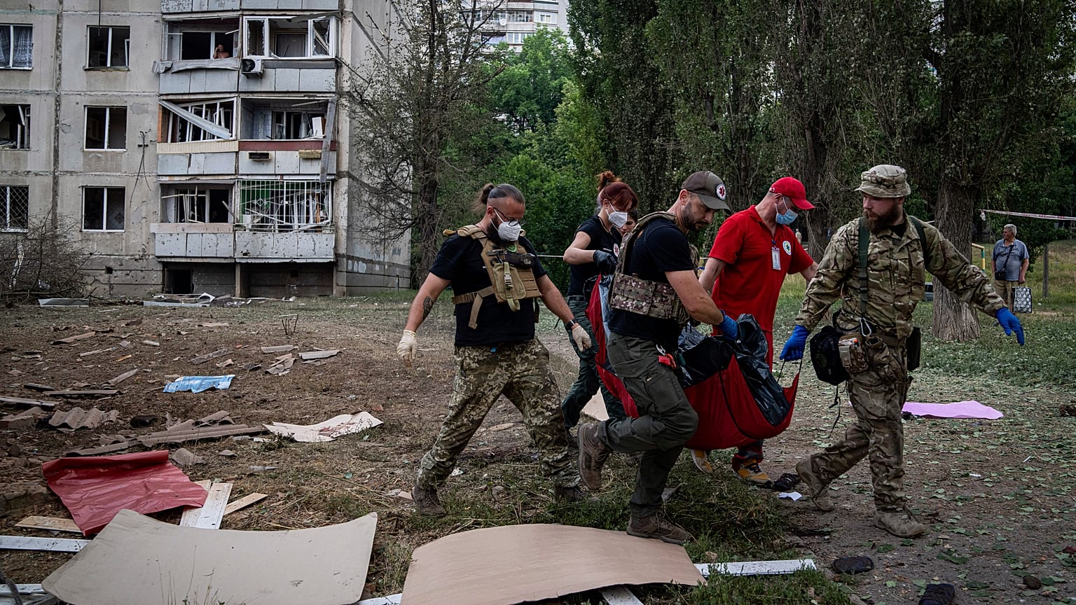 Paramédicos transportam corpo de mulher morta em bombardeamento a Kharkiv, Ucrânia