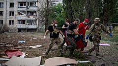Sanitäter tragen die Leiche einer Frau, nach einem russischen Bombardement in Charkiw