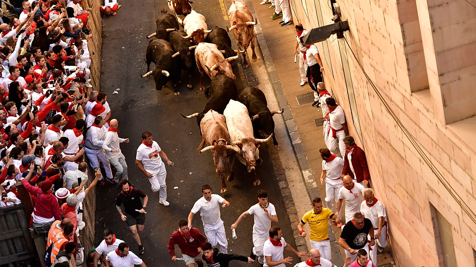 People run through the street with fighting bulls at the San Fermin Festival in Pamplona, northern Spain, Friday, July 8, 2022. 