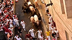 People run through the street with fighting bulls at the San Fermin Festival in Pamplona, northern Spain, Friday, July 8, 2022. 