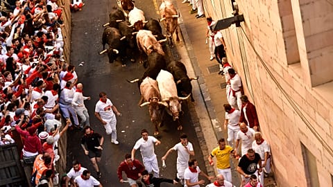 People run through the street with fighting bulls at the San Fermin Festival in Pamplona, northern Spain, Friday, July 8, 2022. 