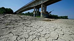 Dry cracked land visible under a bridge in Boretto on the bed of the Po river, Italy, Wednesday, June 15, 2022.