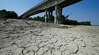 Dry cracked land visible under a bridge in Boretto on the bed of the Po river, Italy, Wednesday, June 15, 2022.
