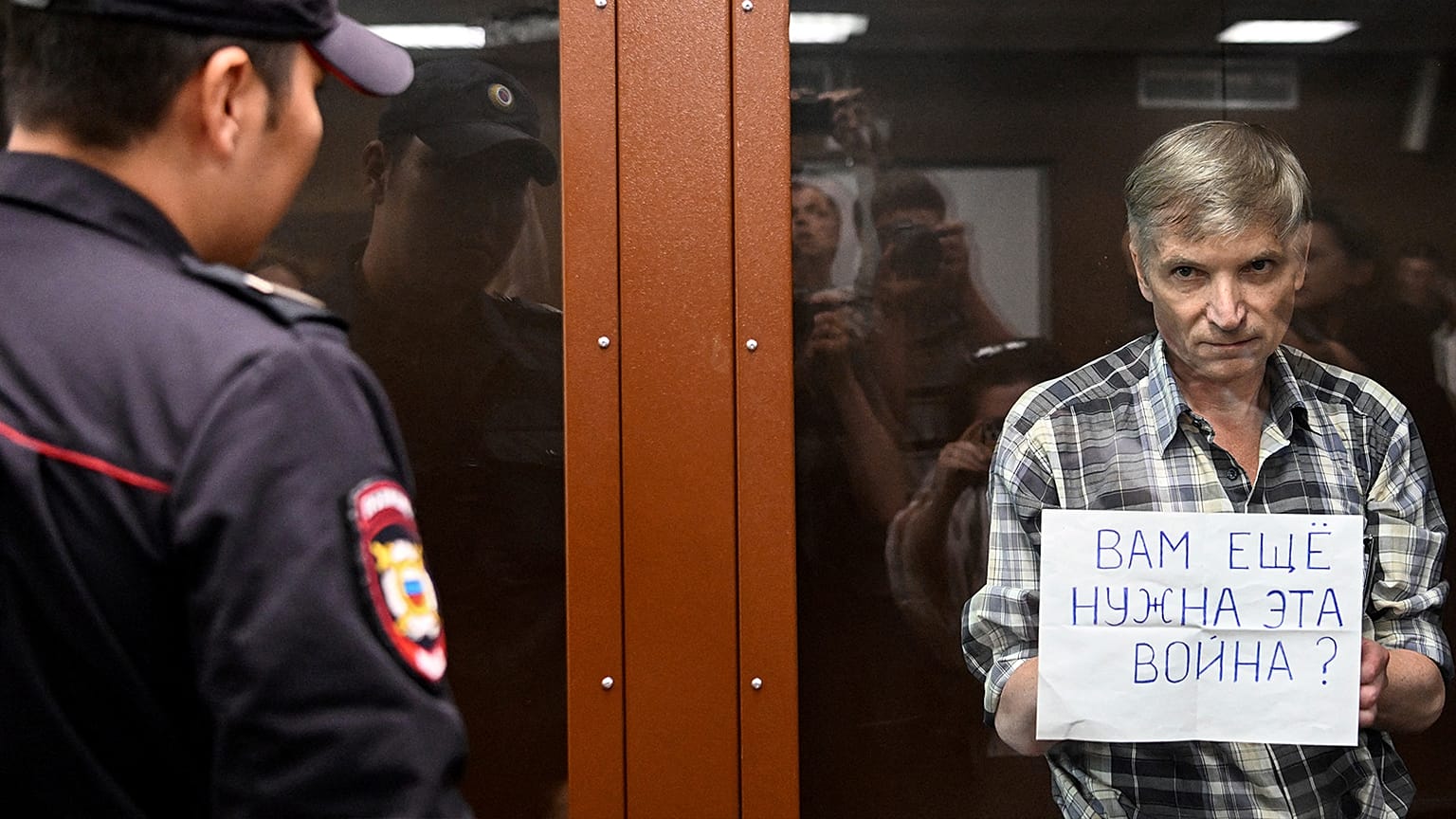 Moscow city councillor Alexei Gorinov shows a sign asking "Do you still need this war?" in court on 8 July 2022
