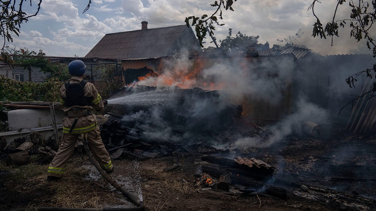 A firefighter hoses down a house on fire after cluster rockets hit a residential area, in Konstantinovka, eastern Ukraine, Saturday, July 9, 2022.