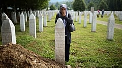 Женщина молится у могилы убитого родственника в мемориальном комплексе в Потокари неподалеку от Сребреницы. 8 июля 2022
