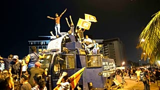 Demonstrierende stehen auf einem zerstörten Wasserwerfer der Polizei am Eingang des Amtssitzes des Präsidenten in Colombo, Sri Lanka