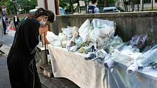 A mourner offers a flower for former Japanese Prime Minister Shinzo, at the entrance of the Liberal Democratic Party (LDP) HQ building in Tokyo, Japan,  Sunday July 10, 2022. 