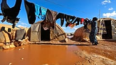 Eine Frau hängt in einem Flüchtlingslager in der Provinz Idlib, Syrien, Wäsche auf.