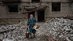 Une femme récupère des affaires personnelles, après qu'une roquette ait frappé un immeuble d'habitation, à Chasiv Yar, le 10 juillet 2022