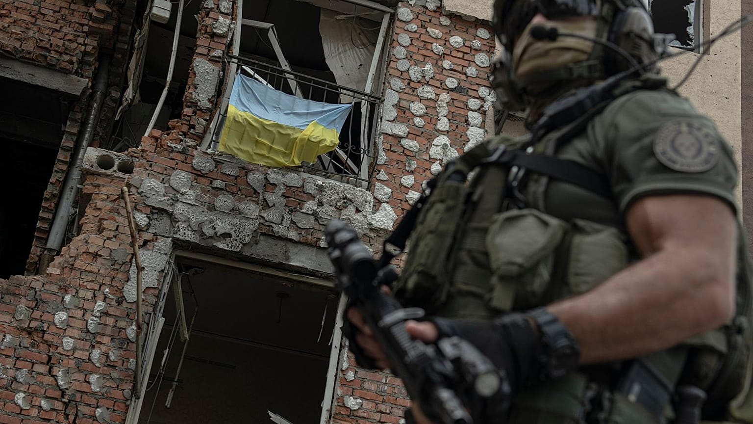 A Ukrainian serviceman is backdropped by a destroyed building in Irpin, Ukraine, Monday, July 11, 2022.