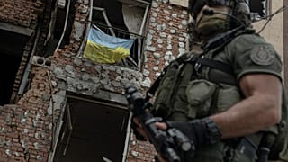 A Ukrainian serviceman is backdropped by a destroyed building in Irpin, Ukraine, Monday, July 11, 2022.