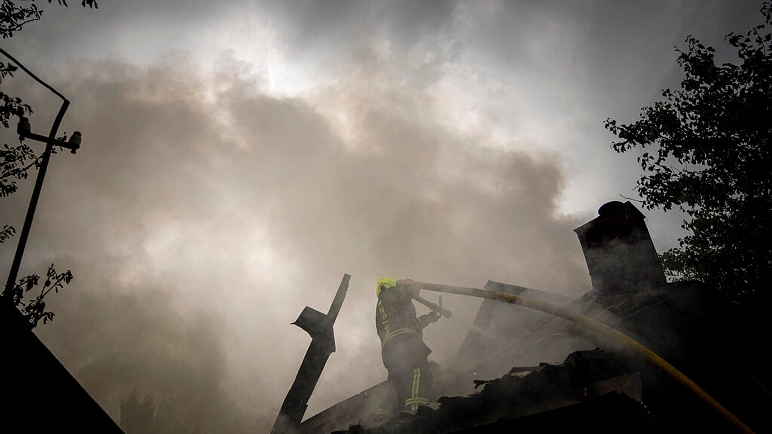 Un secouriste éteint l'incendie d'une maison détruite après une attaque russe dans un quartier du centre-ville de Kharkiv, le 11 juillet 2022.