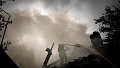 Un secouriste éteint l'incendie d'une maison détruite après une attaque russe dans un quartier du centre-ville de Kharkiv, le 11 juillet 2022.