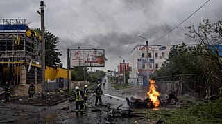 Украинские спасатели работают на месте ракетного удара по жилому квартала в Харькове